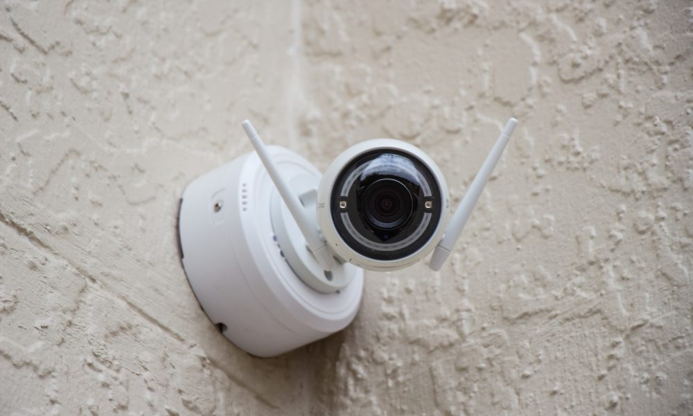 white surveillance camera hanging on wall