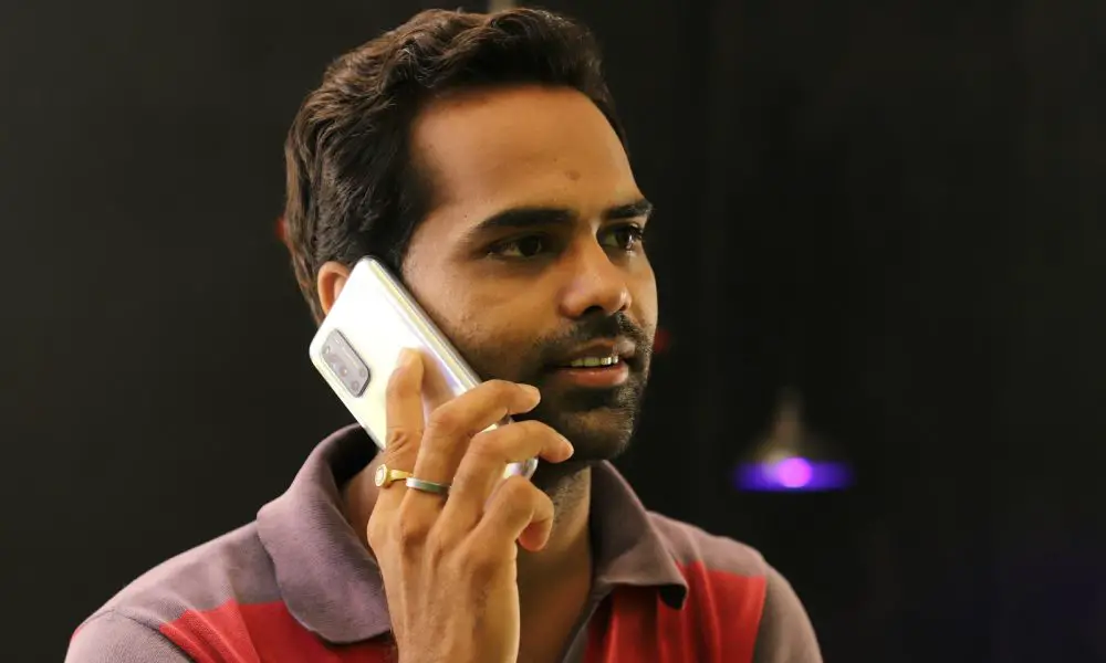 man in red and gray hoodie holding white smartphone