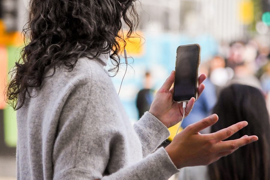 woman in gray sweater holding smartphone