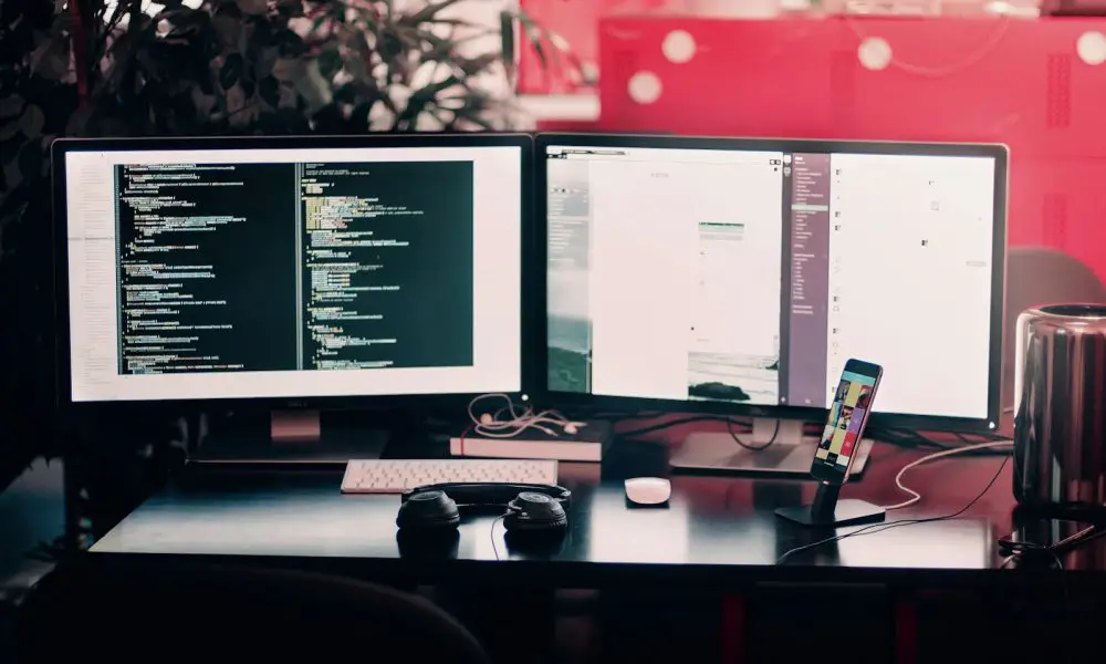 two black computer monitors on black table