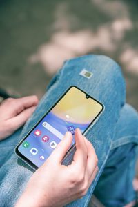 A person sitting on the ground holding a cell phone