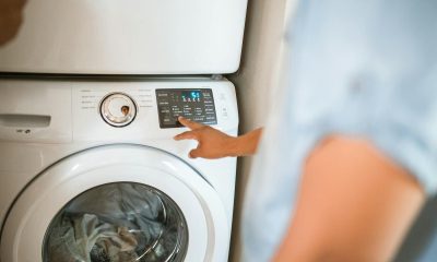 Hand selecting laundry options on a digital washing machine control panel indoors.