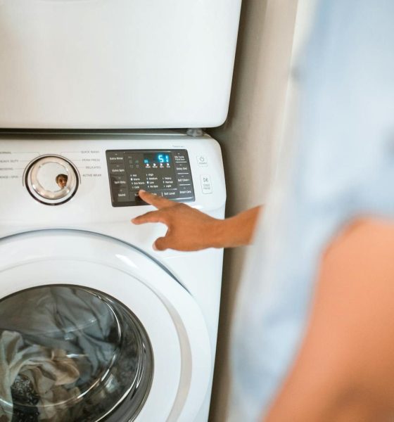 Hand selecting laundry options on a digital washing machine control panel indoors.